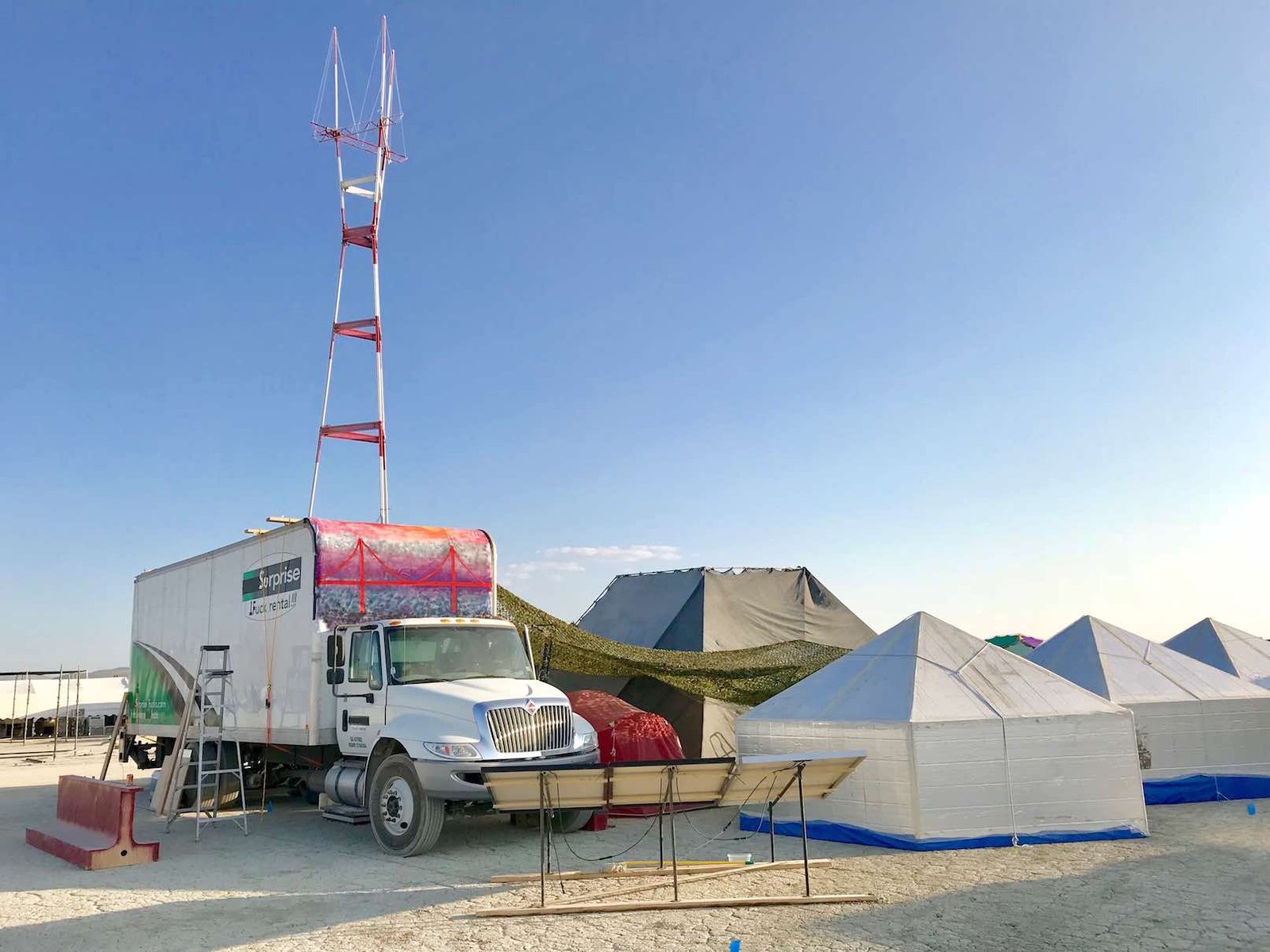 The flagship Surprise Fuck Rental truck on the playa in 2017, with a scaffolding tower and Golden Gate Bridge mural on the box